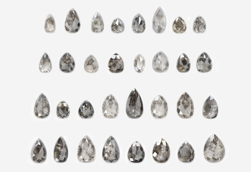 four rows of loose pear shaped salt and pepper diamonds on white background