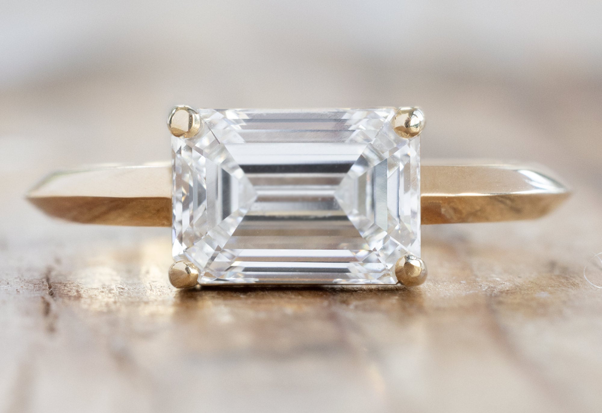 The Bryn Ring with an Emerald-Cut Lab Grown Diamond on Wood Table
