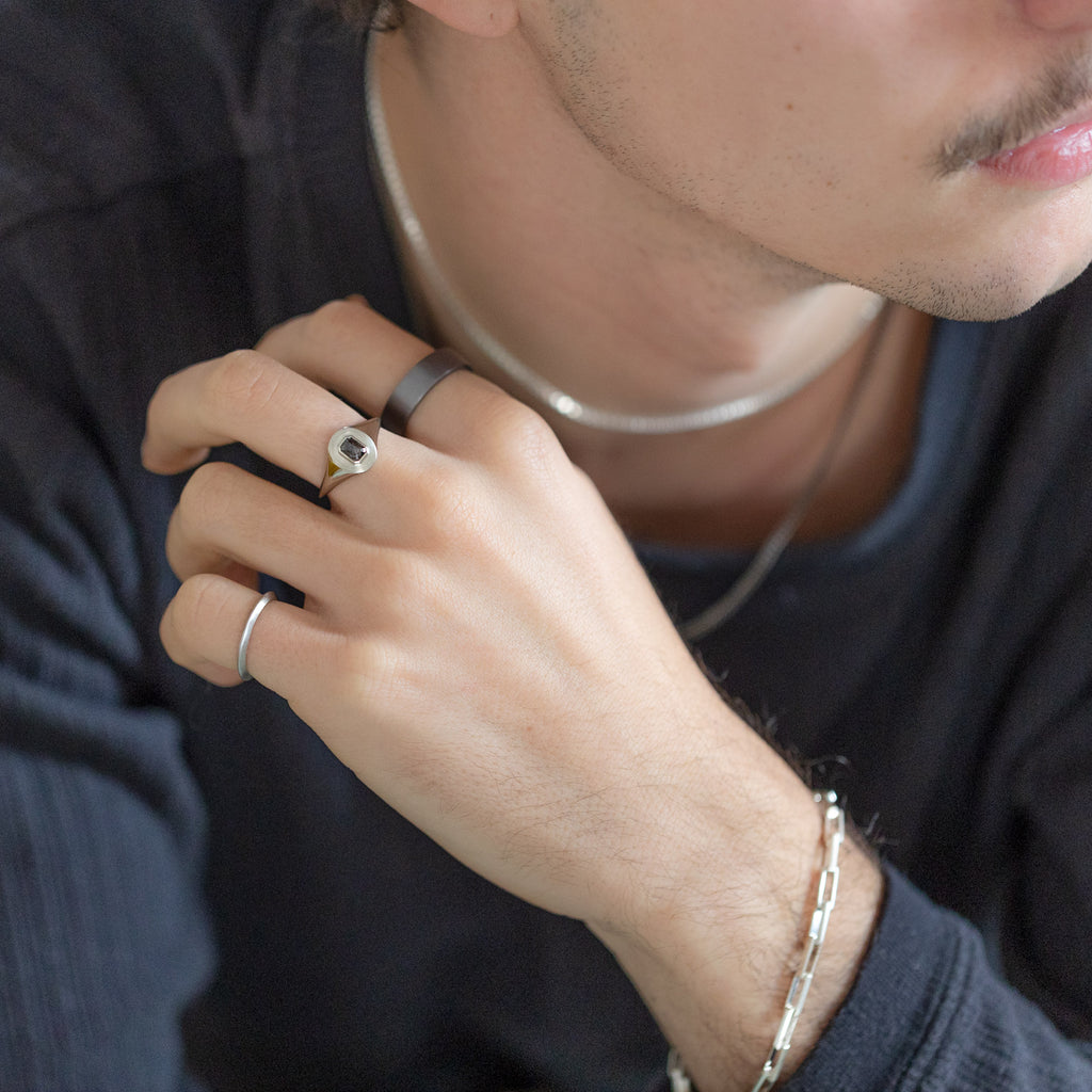 The Emerald-Cut Black Diamond Signet Ring Stylized on Model wearing other fine jewelry pieces