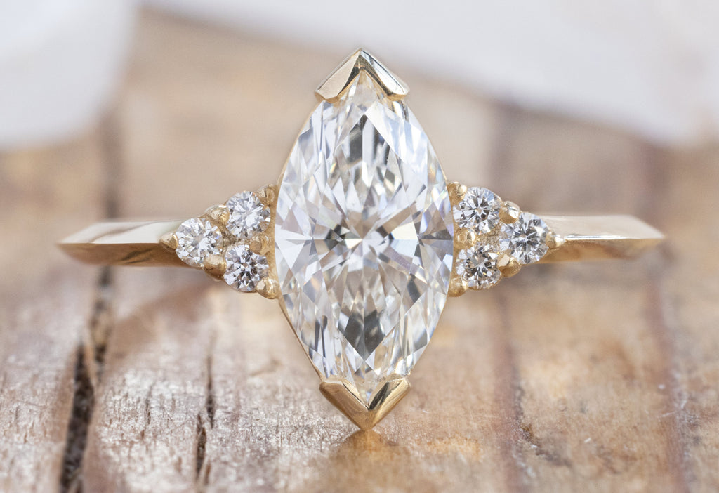 The Ivy Ring with a Lab Grown Marquise Diamond on Wood Table
