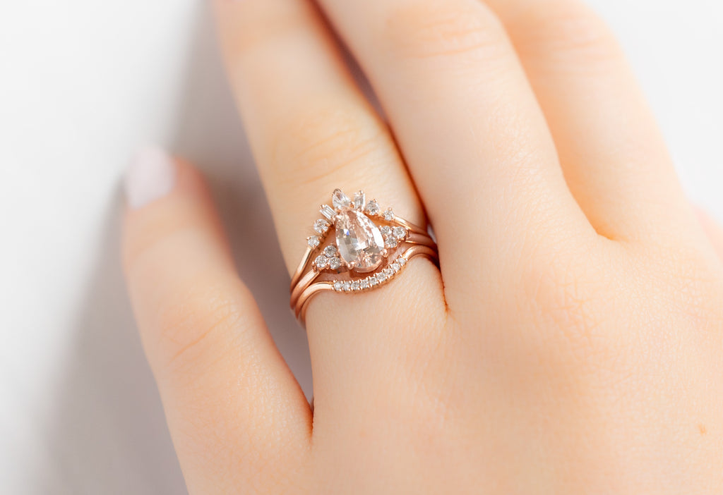 The Ivy Ring with a Pear-Cut Peach Sapphire with White Diamond Stacking Bands on Model