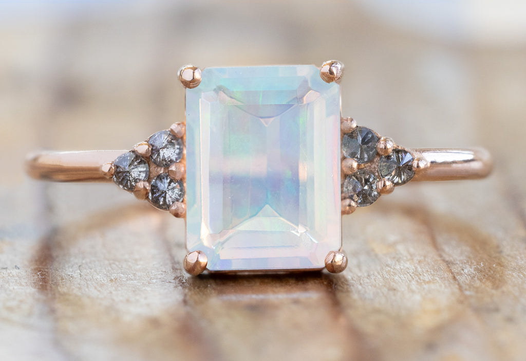 The Ivy Ring with an Emerald-Cut Opal on Wood Table