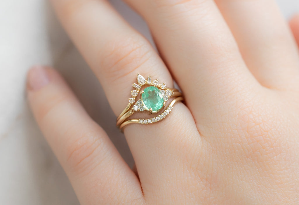 The Ivy Ring with an Oval-Cut Emerald with White Diamond Stacking Bands on Model