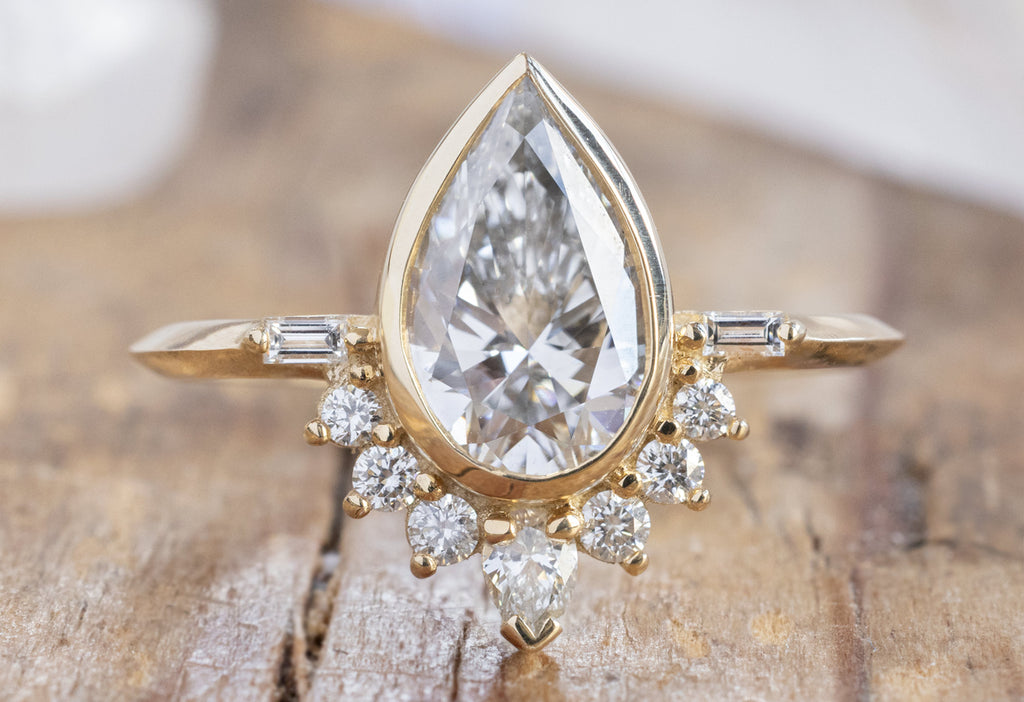 The Posy Ring with a Pear-Cut Lab Grown Diamond on Wood Table