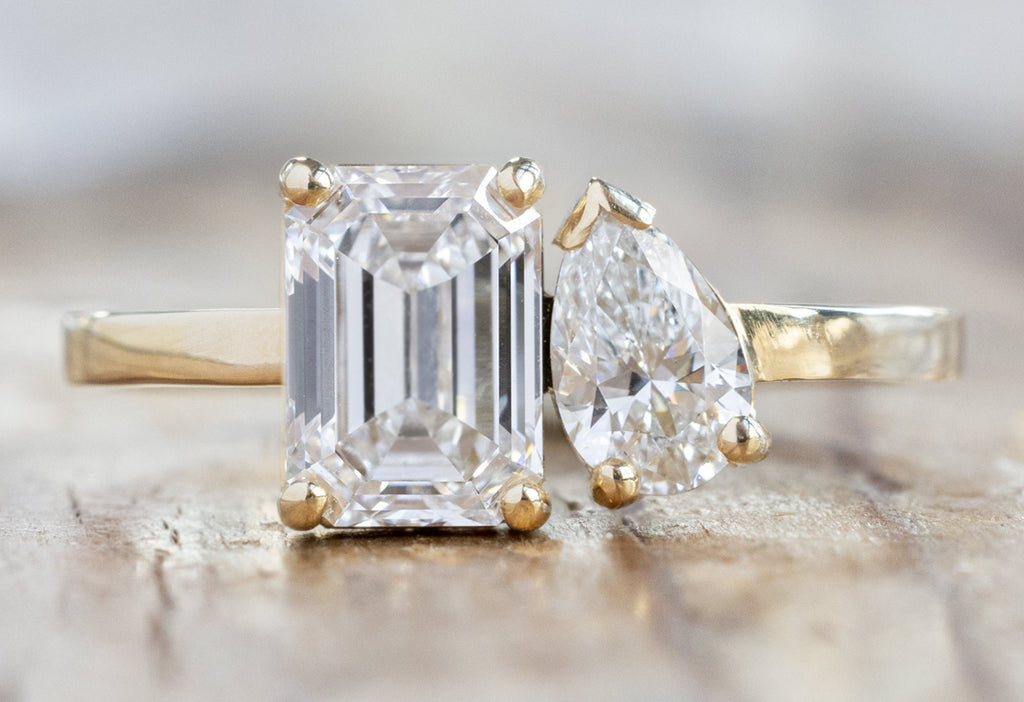 The You & Me Ring with an Emerald-Cut Lab Grown + White Diamond on Wood Table