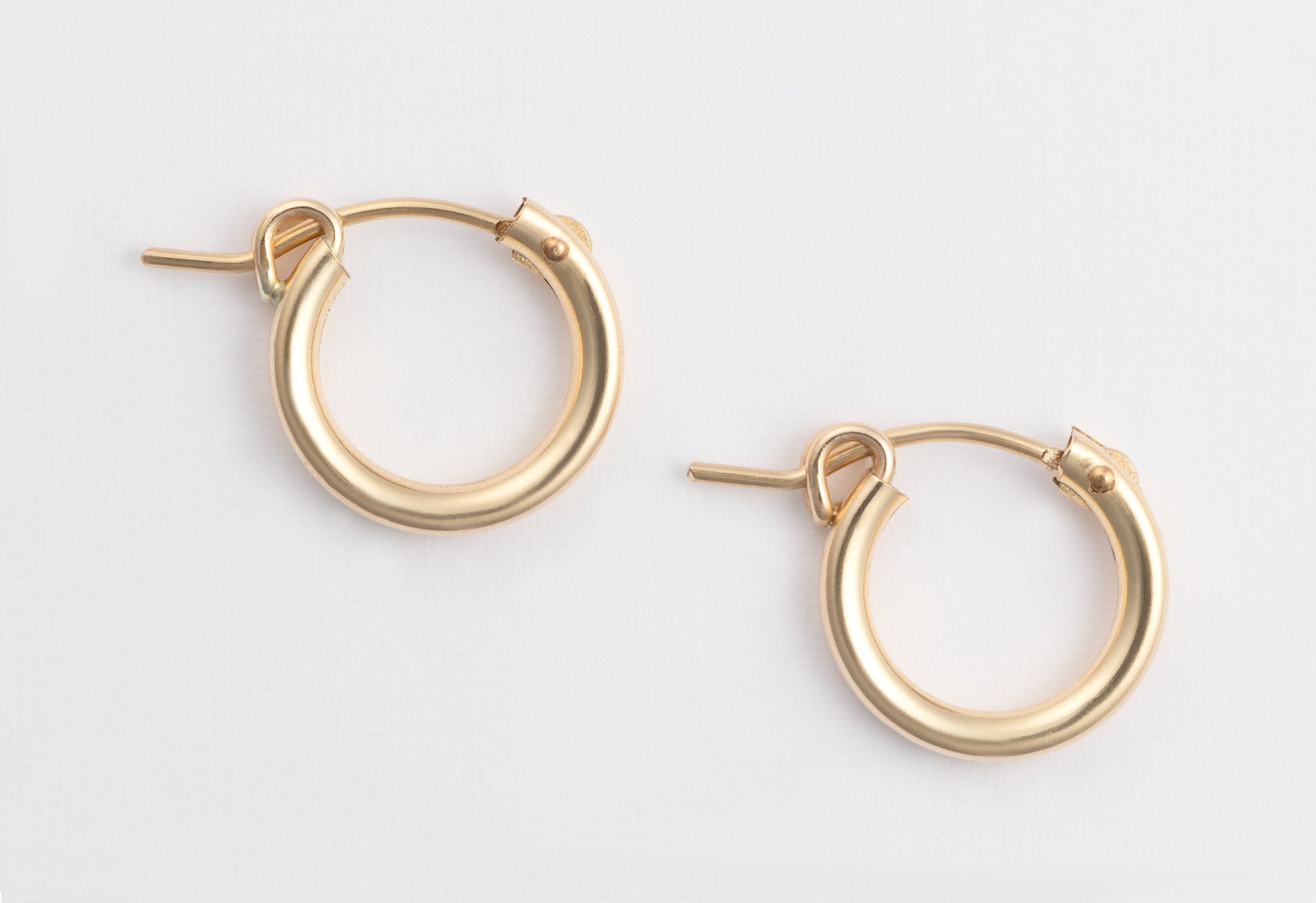 Yellow Gold Charm Hoop Earrings on White Textured Paper
