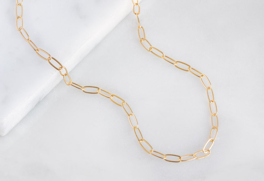 Yellow Gold The Drawn Cable Chain Charm Bracelet on White Marble Tile