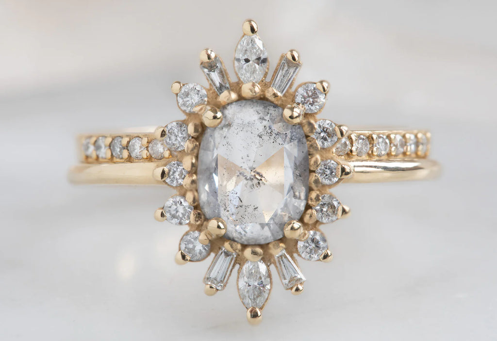 The Camellia Ring with an Oval-Cut Salt and Pepper Diamond with the Open Cuff Pavé Diamond Stacking Band on White Marble Tile