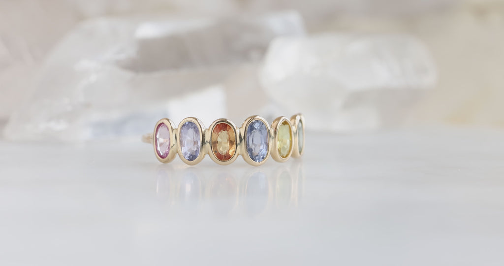 yellow gold Rainbow Gemstone Eternity Ring on white marble tile