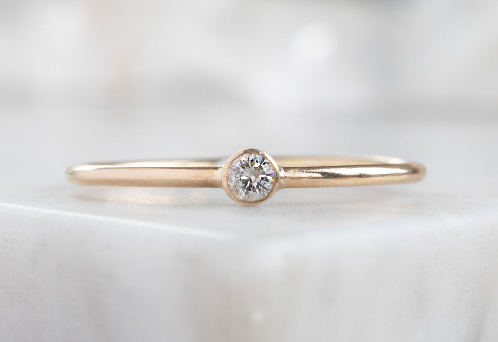 yellow gold Teensy Custom Diamond Stacking Ring on white marble tile