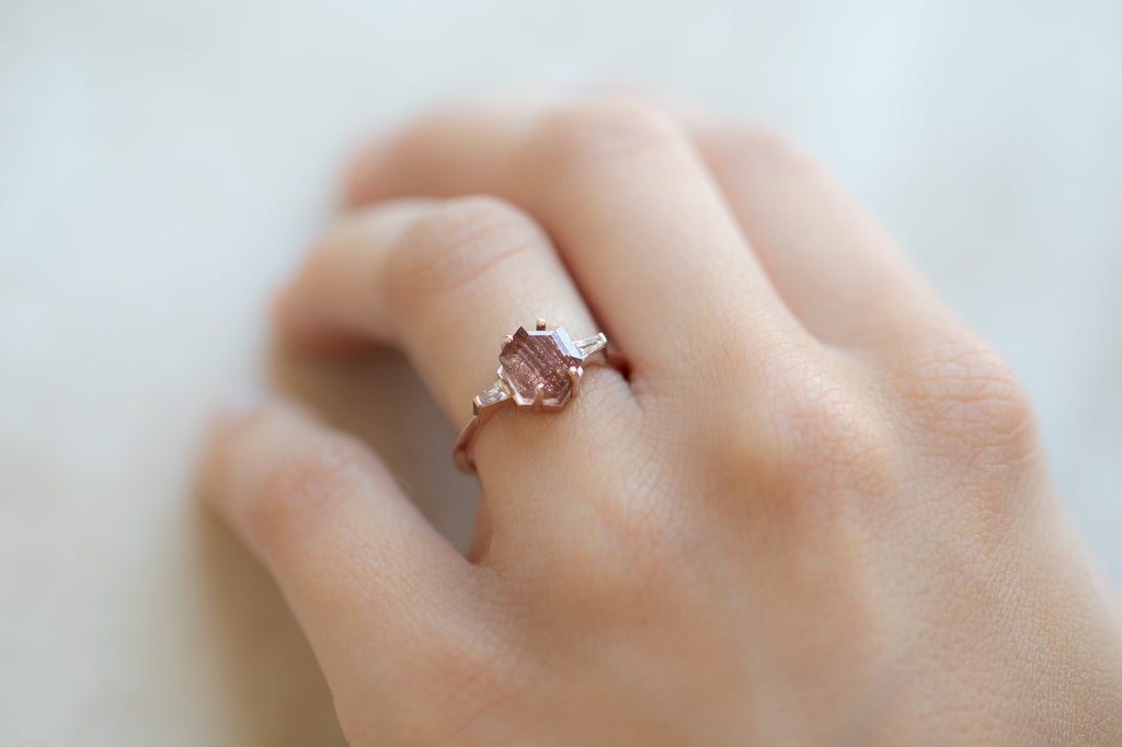 The Ash Ring with a Sunstone Hexagon on hand
