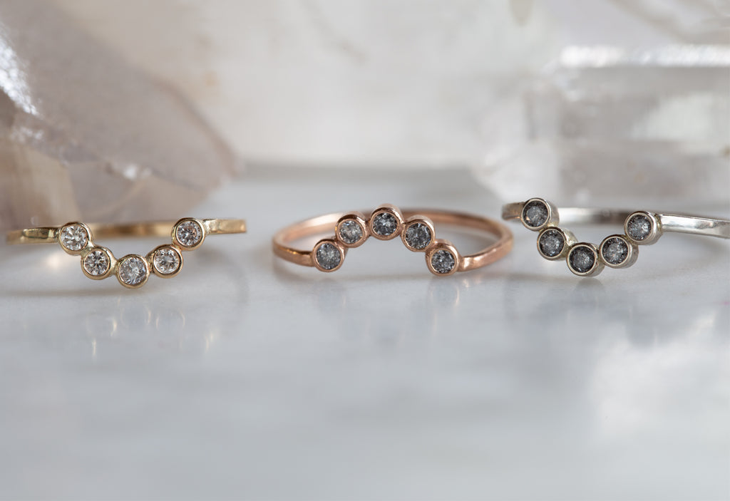 Three Diamond Bezel Arc Rings in yellow, white and rose gold on white marble tile