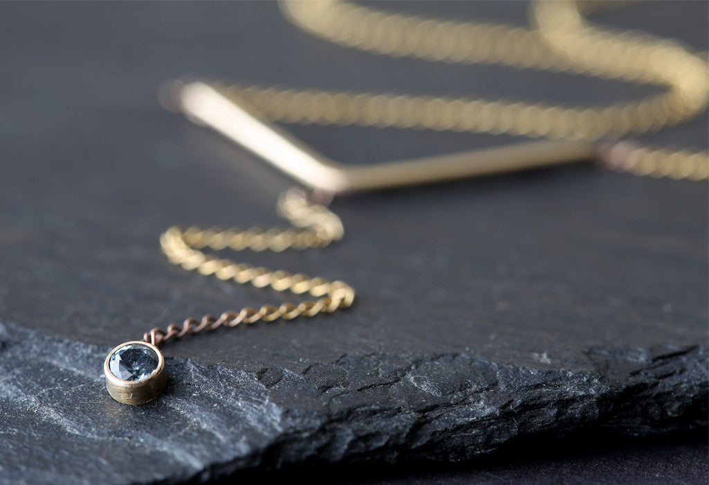 Yellow Gold Peak Sapphire Lariat Necklace on black slate