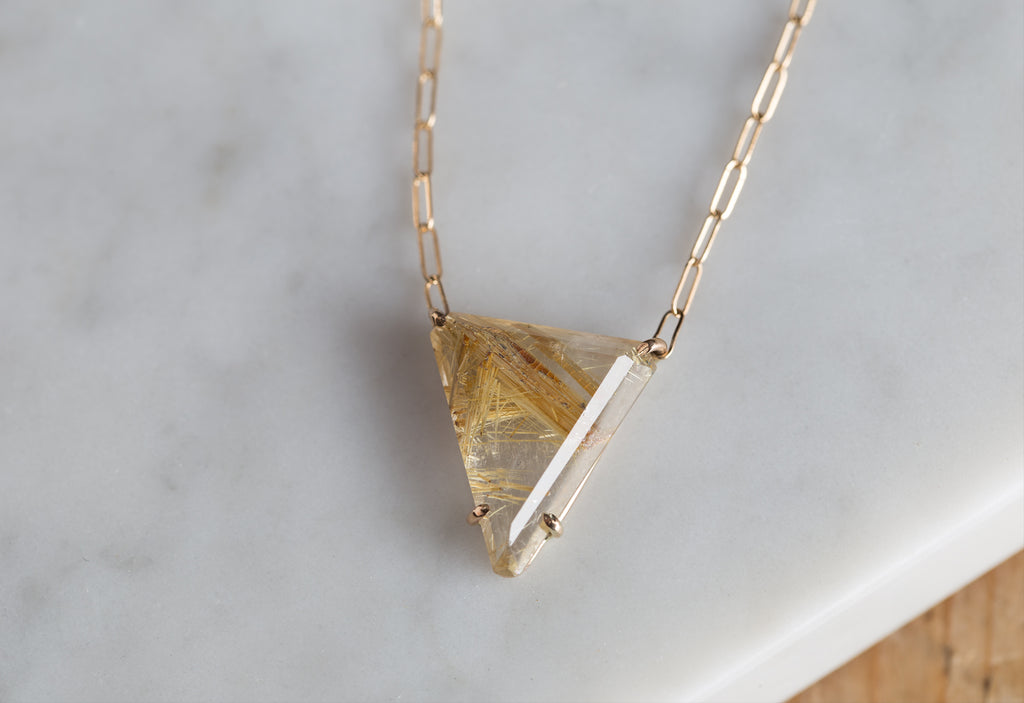 yellow gold rutilated quartz pendant necklace on white marble tile