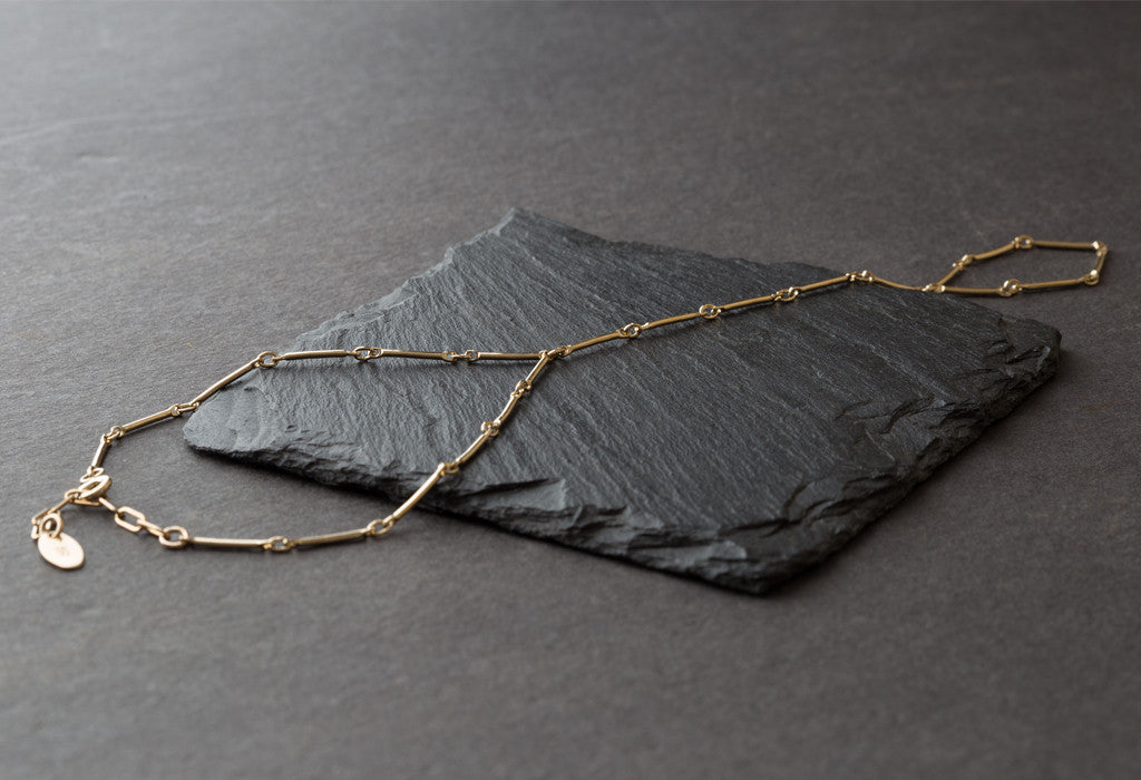 Yellow Gold Bar Chain Hand Piece on black slate