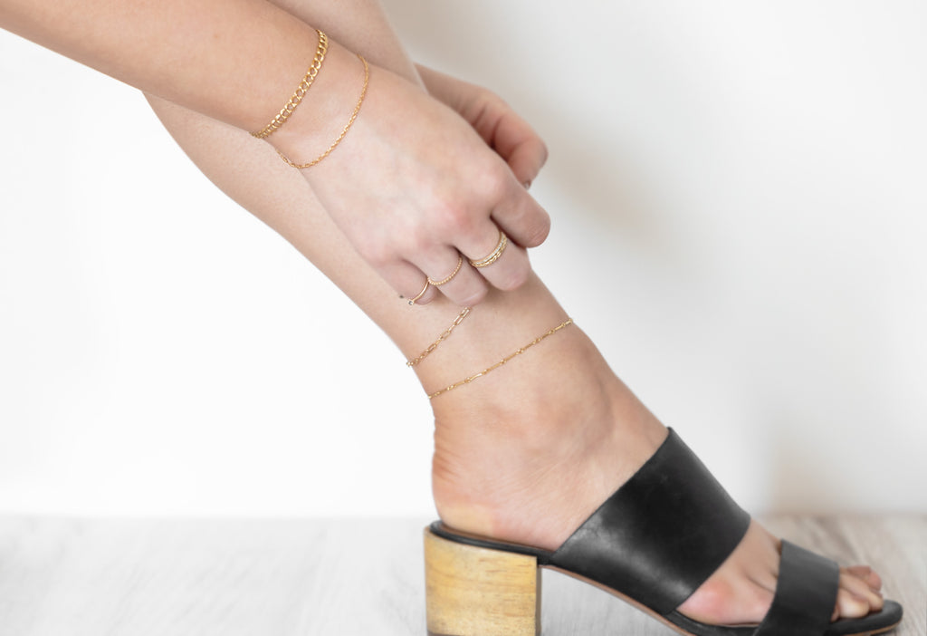 Model Putting on Anklet in Black Mule Sandals
