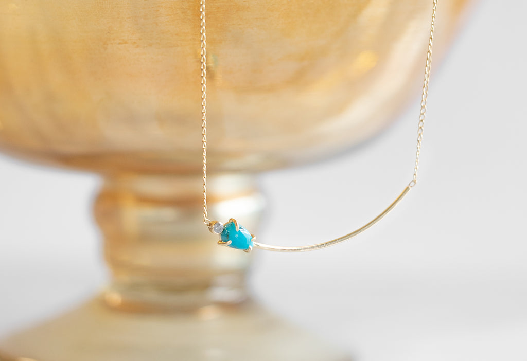 Asymmetrical Turquoise + Diamond Necklace Hanging from Bowl