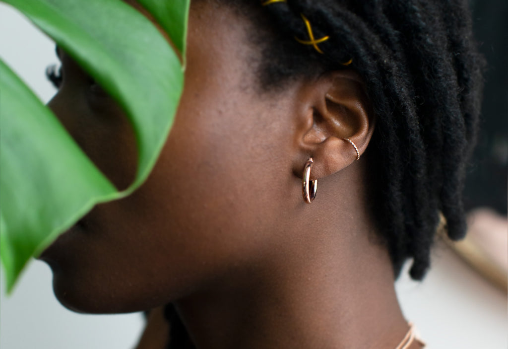 Rose Gold Small Hoop Earrings on Model amongst greenery 