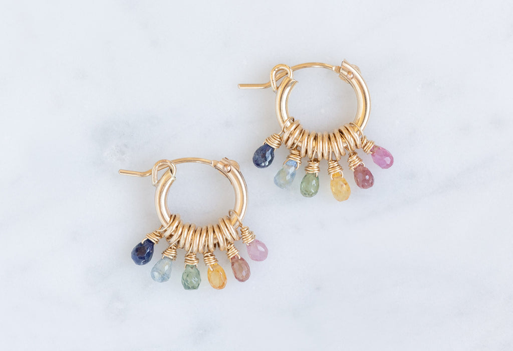 Rainbow Sapphire Hoop Earrings Flat on White Marble Tile