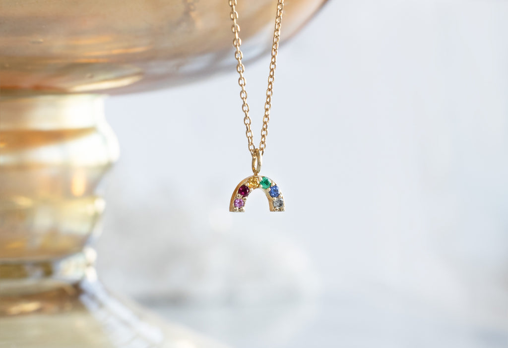 Rainbow Sapphire Necklace Hanging on Gold Bowl