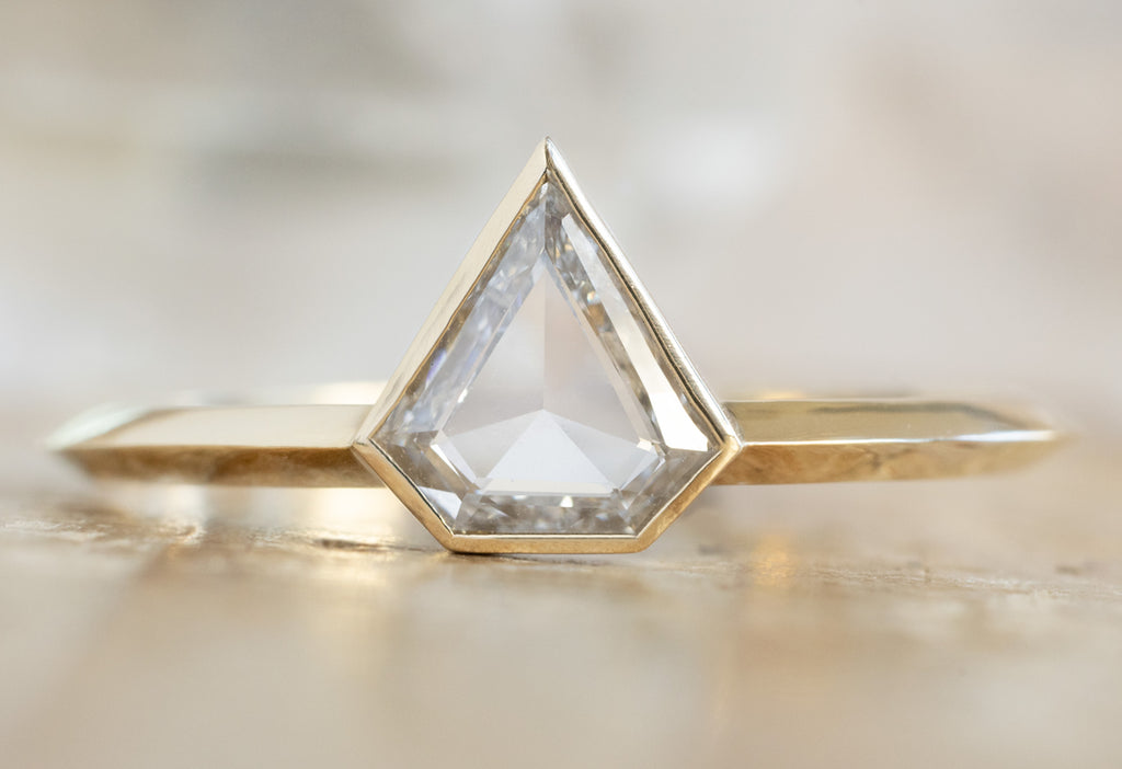 The Hazel Ring with a Shield-Cut White Diamond on Wood Table
