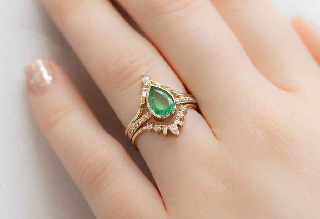 The Willow Ring with a Pear-Cut Emerald with White Diamond Stacking Bands on Model