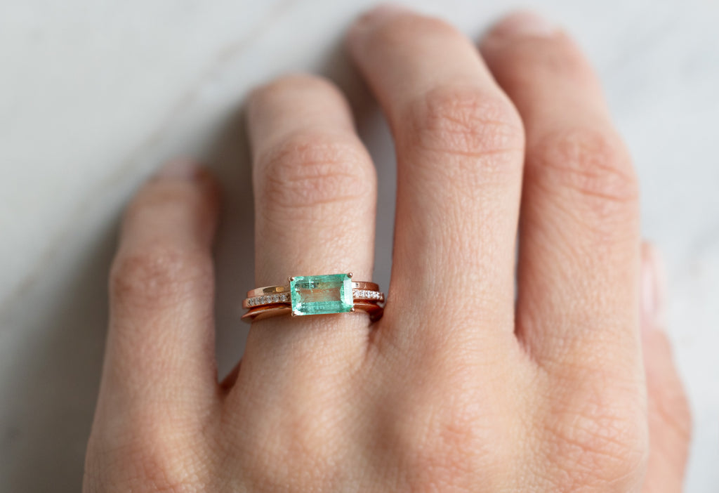 The Willow Ring with an Emerald Cut Emerald with Stacking Bands on Model