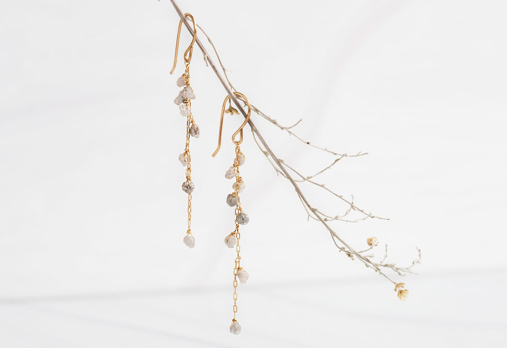 Yellow Gold Rough Diamond Cascade Earrings hanging on dried flower stem