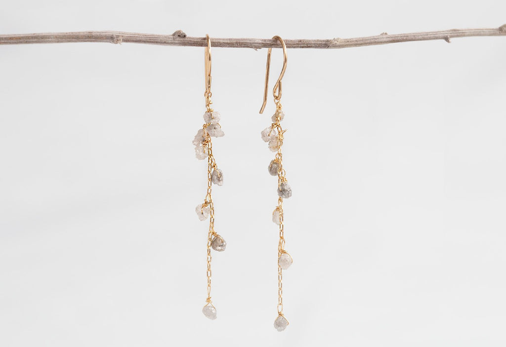 Yellow Gold Rough Diamond Cascade Earrings hanging on dried flower stem