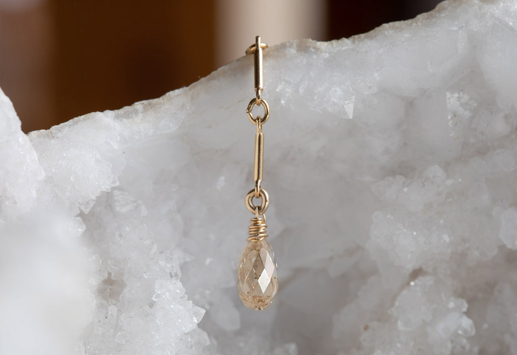 up close yellow gold champagne briolette lariat necklace draped over white druzy crystal