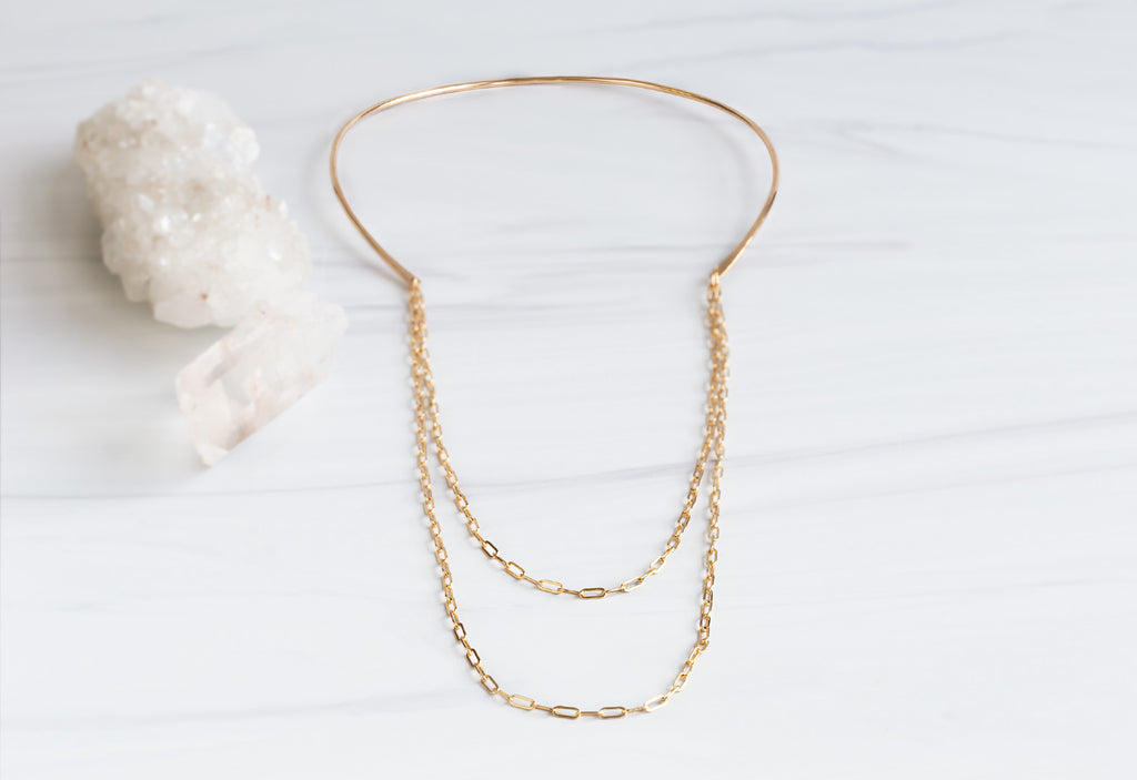 Yellow Gold Chained Open Cuff Necklace on White Marble Tile