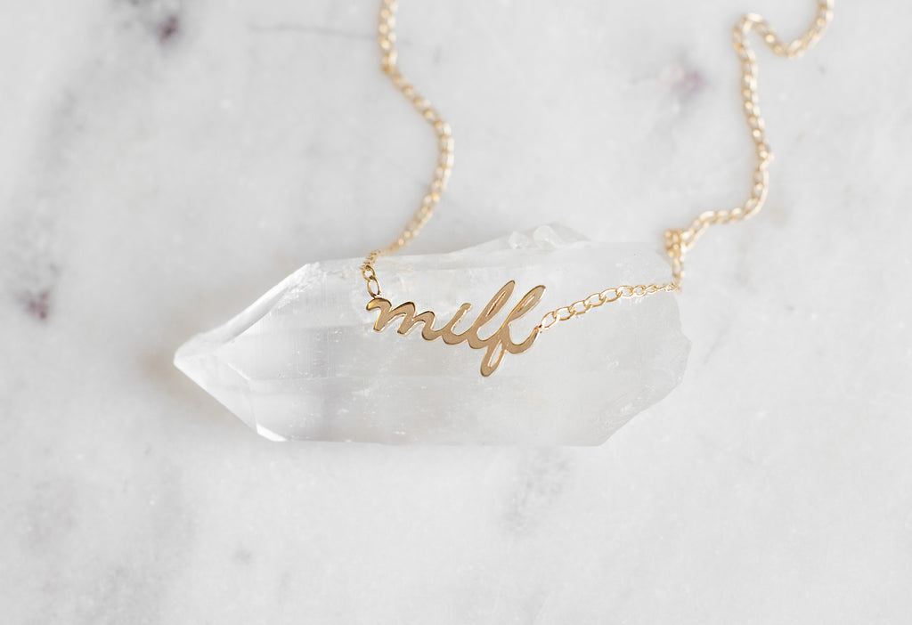 'Milf' Necklace laying on hexagonal white crystal