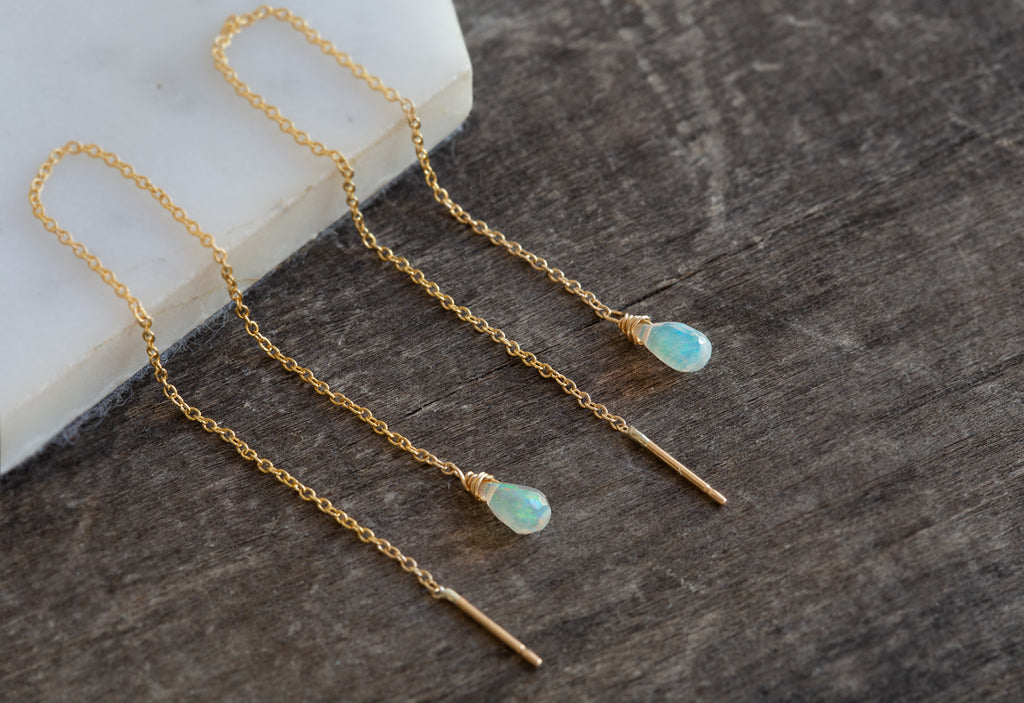 Natural Opal Thread Earrings on white marble tile and wood table