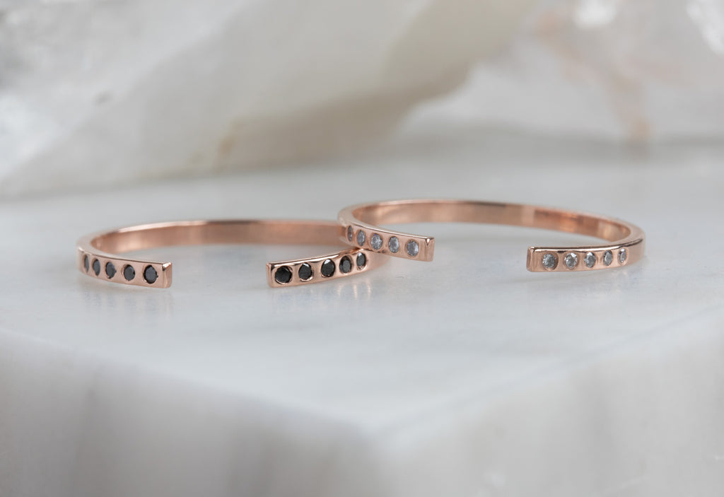 two rose gold Open Cuff Flush Set Pavé Diamond stacking bands on white marble tile