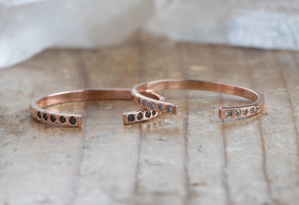two rose gold Open Cuff Flush Set Pavé Diamond stacking bands on wood table
